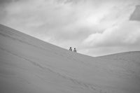 two people standing on top of a sand dune
