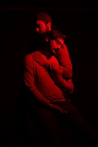 two men hugging each other in a dark room