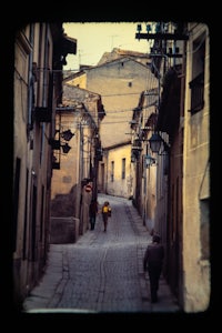two people walking down a cobblestone street