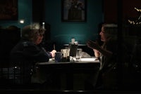 two people sitting at a table in a restaurant at night