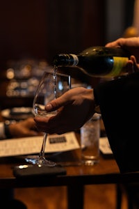 a person pouring wine into a glass