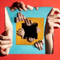 a group of hands reaching through a square frame on a red background