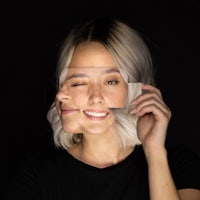 a woman is holding her face up to a black background