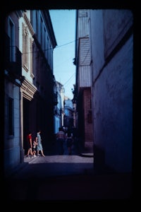 a group of people walking down a narrow alley